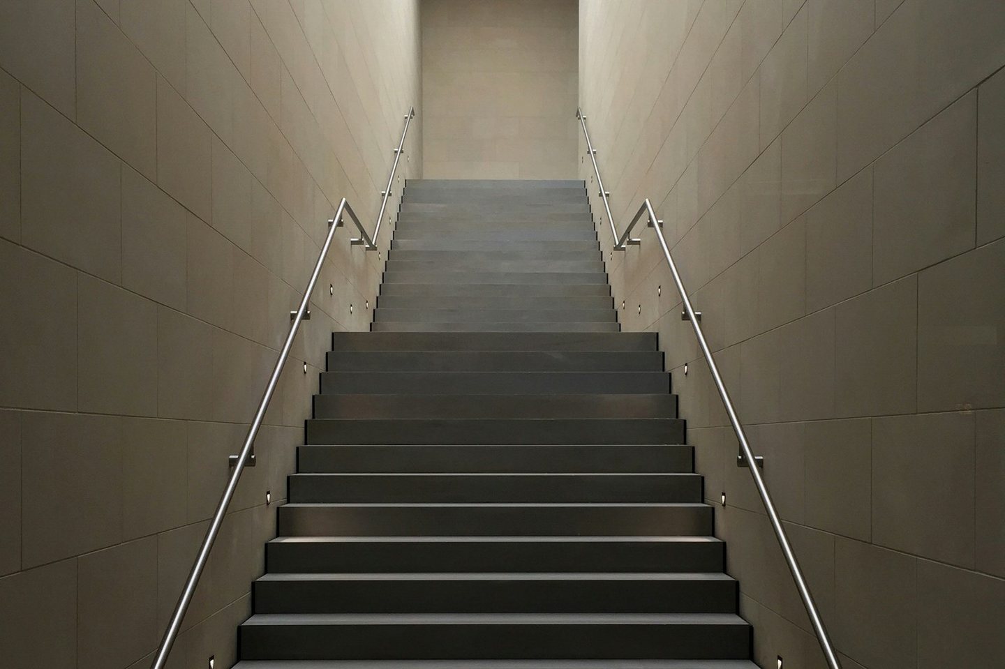 A concrete staircase rising toward a lit opening